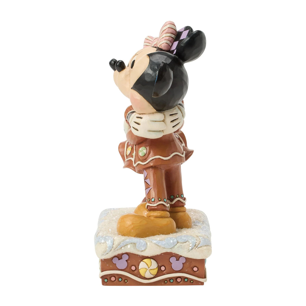 Vista laterale: profilo di Minnie con fiocco rosa a righe e orecchio a scacchi lilla, e fianco della base con caramelle a girandola e sagome di Topolino lilla