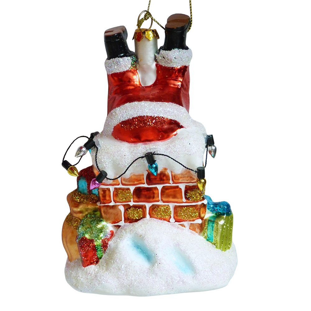 Addobbo di vetro Babbo Natale a testa in giù nel camino, con gli stivali neri in alto, mattoni rossi, lucine colorate, pacchetti regalo e neve glitterata
