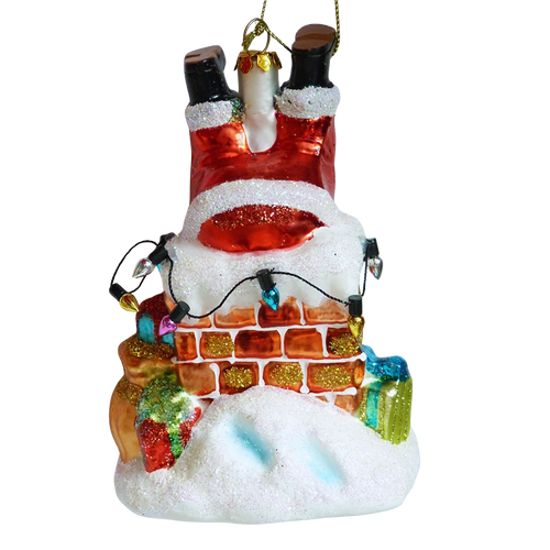 Addobbo di vetro Babbo Natale a testa in giù nel camino, con gli stivali neri in alto, mattoni rossi, lucine colorate, pacchetti regalo e neve glitterata