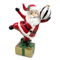 Decorazione natalizia in poliresina, Babbo Natale danzante su un pacco regalo dorato con palla di Natale a righe bianche e nere