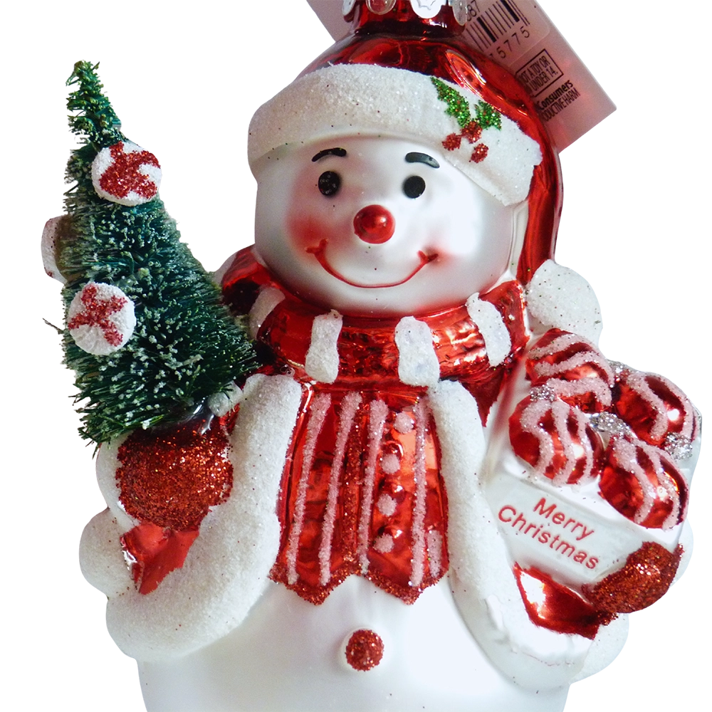 Primo piano del pupazzo di neve con gilet rosso a righe glitterate, alberello verde e scatola di caramelle con scritta Merry Christmas