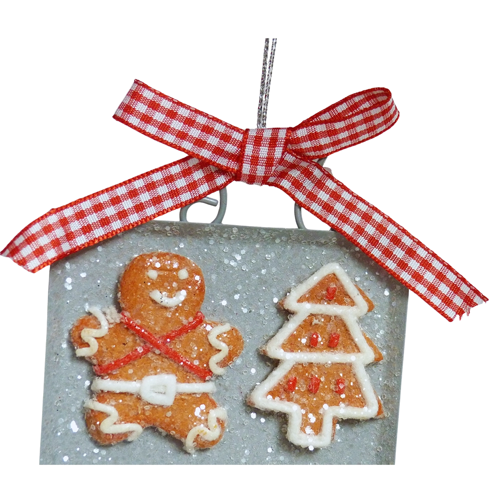 Dettaglio del fiocco a quadretti rossi e bianchi sulla teglia, con un omino di pan di zenzero con bretelle rosse incrociate e un alberello glassato