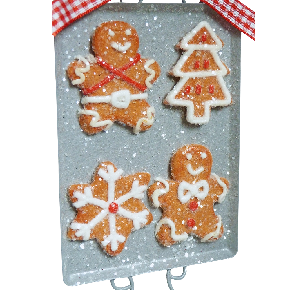 Dettaglio della teglia con quattro biscotti di pan di zenzero glassati: un omino con bretelle rosse e cintura bianca, un alberello, un fiocco di neve e un omino con papillon bianco
