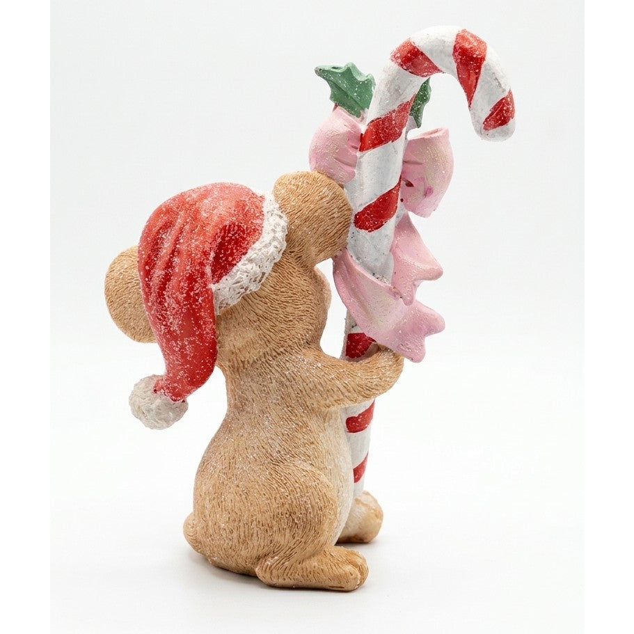 Topino natalizio visto da dietro con cappello da Babbo Natale e pompon bianco, mentre abbraccia un bastoncino di zucchero