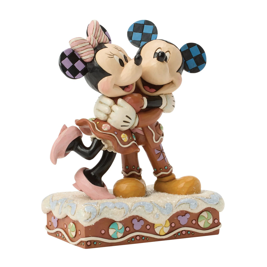 Topolino e Minnie visti di tre quarti da destra, abbracciati con i musi vicini, Minnie con una scarpina rosa sollevata dietro di sé